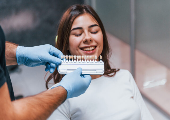 dentist checks level of teeth whitening with color. young adult woman have a visit in the clinic
