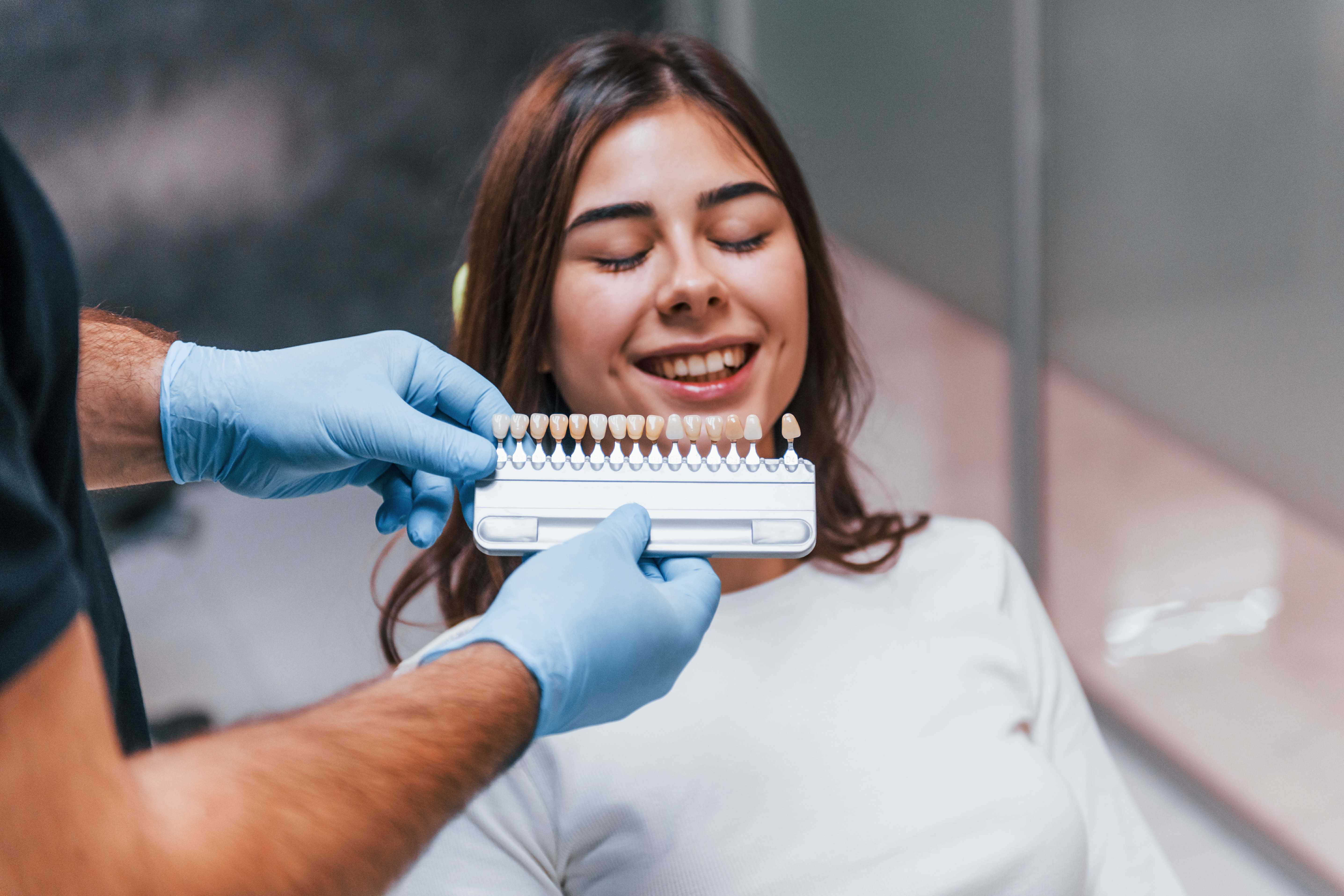 dentist checks level of teeth whitening with color. young adult woman have a visit in the clinic