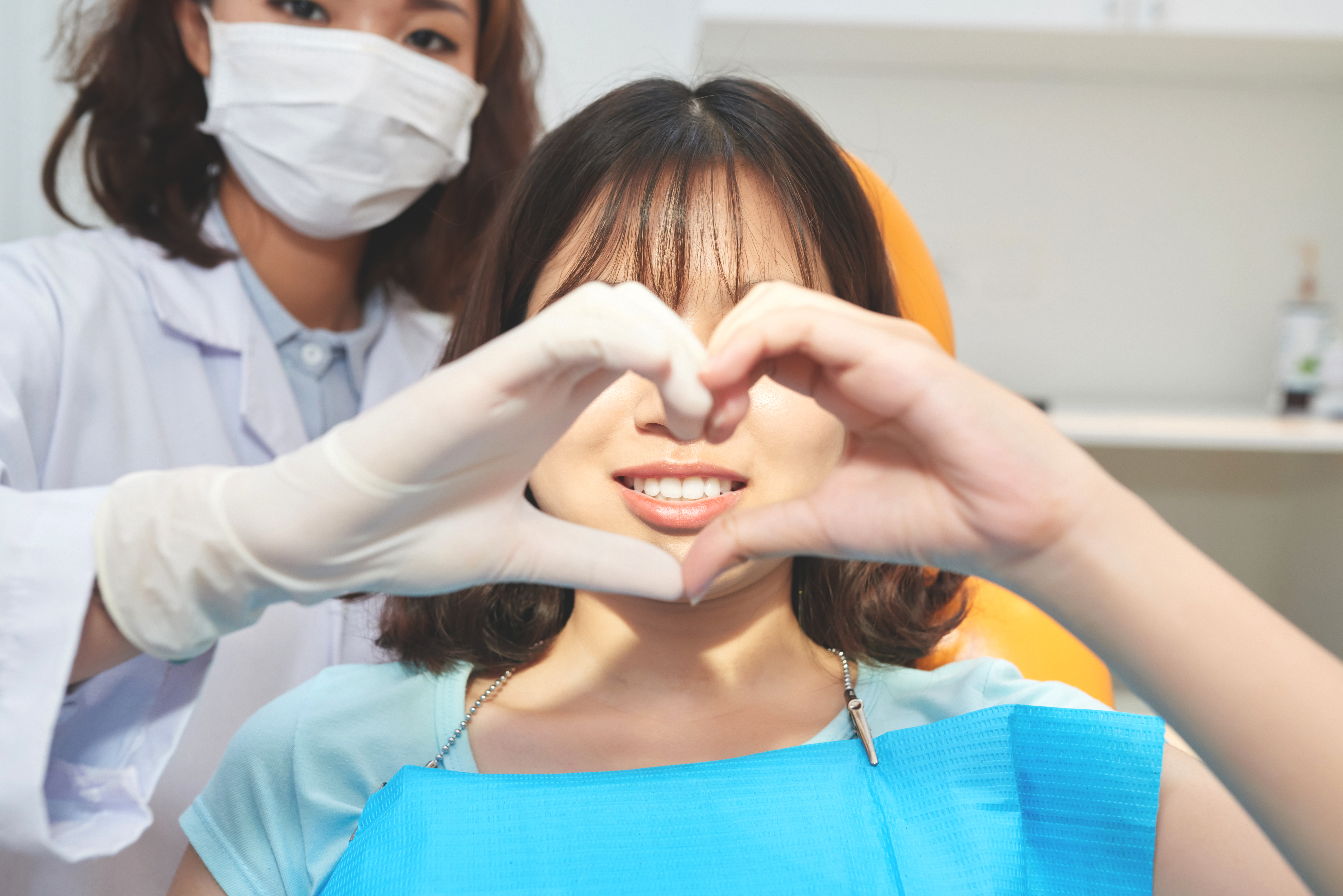 young woman with doctor making heart symbol