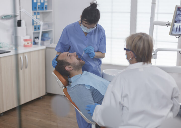 specialist nurse wearing face mask while analyzing patient teeth