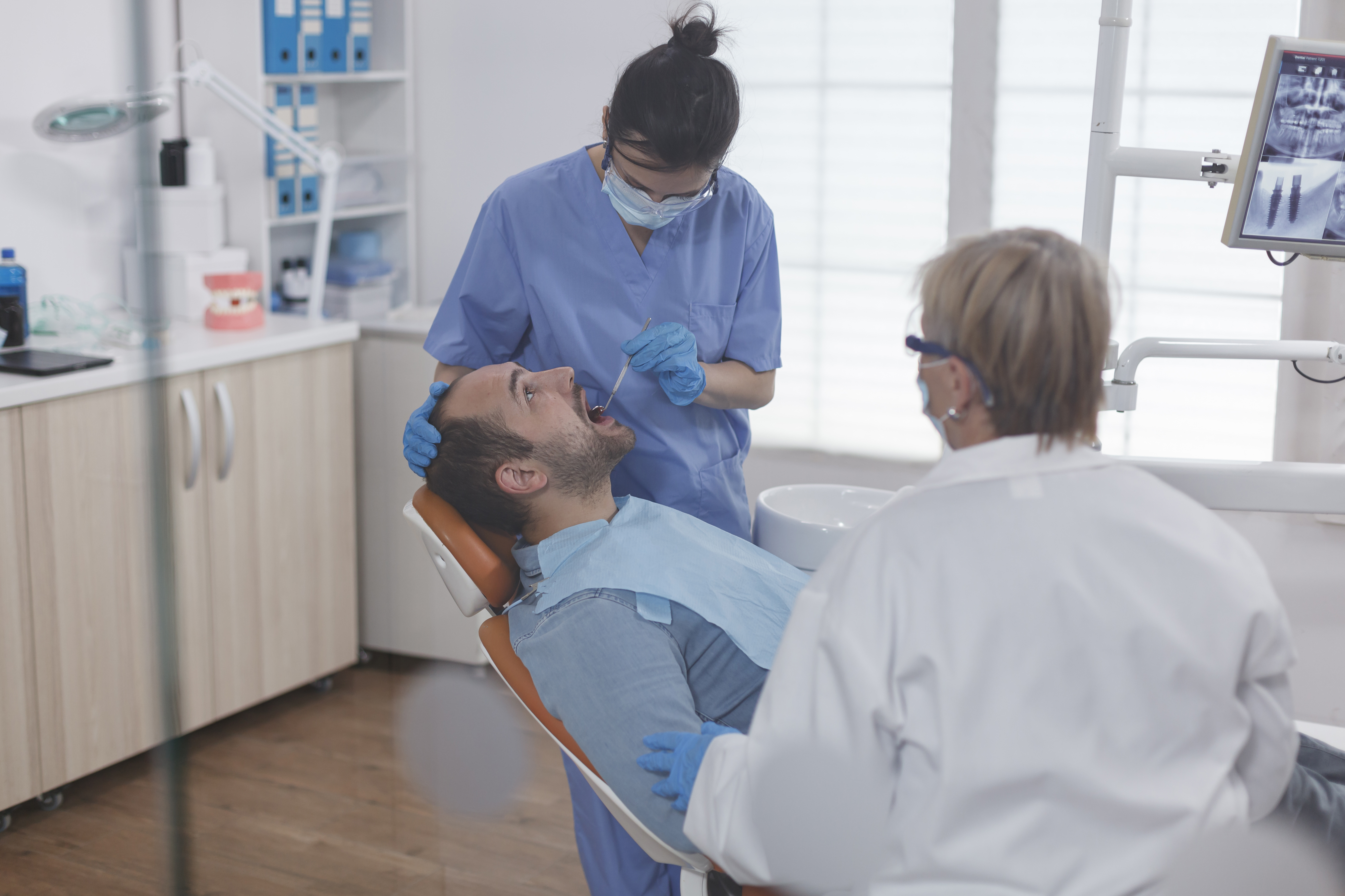 specialist nurse wearing face mask while analyzing patient teeth